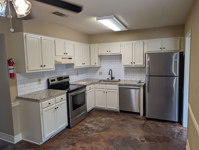 Kitchen with white cabinets, granite counters, tile backsplash, and stainless range, dishwasher, and refrigerator