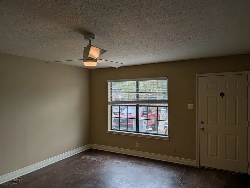 Living room with front window, ceiling fan, and front door