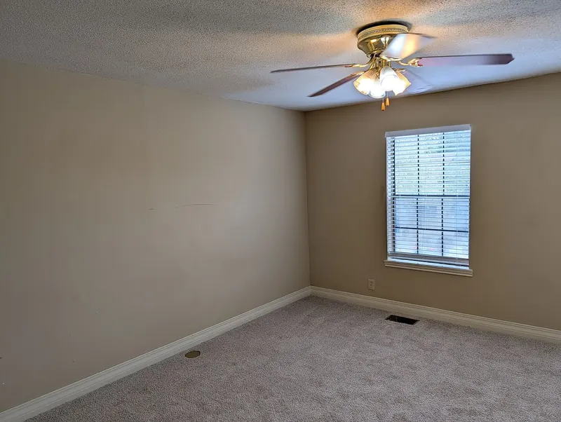 Bedroom with new carpet, ceiling fan, and window