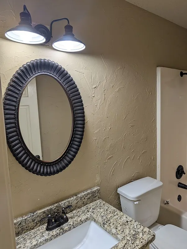 Full bath vanity with granite top and oval mirror