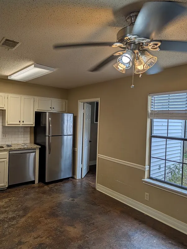 Dining area beside the kitchen with stainless refrigerator, ceiling fan, and window